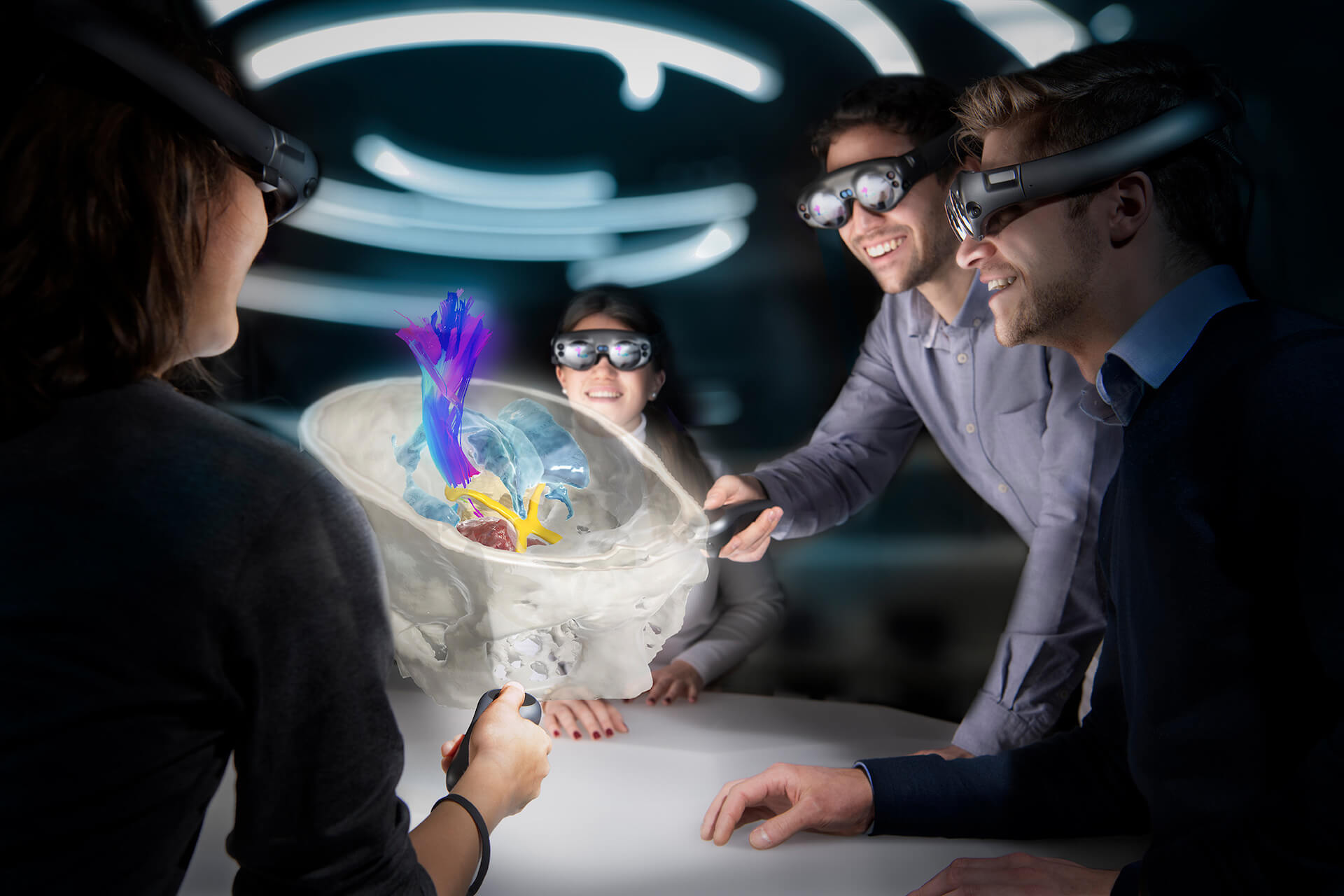 Four people wearing augmented reality glasses lean in around a table to examine a digital image of a skull and brain fiber tracts