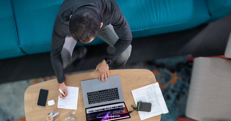 A Brainlab employee studying with a laptop and notes for Brainlab Online Campus training.