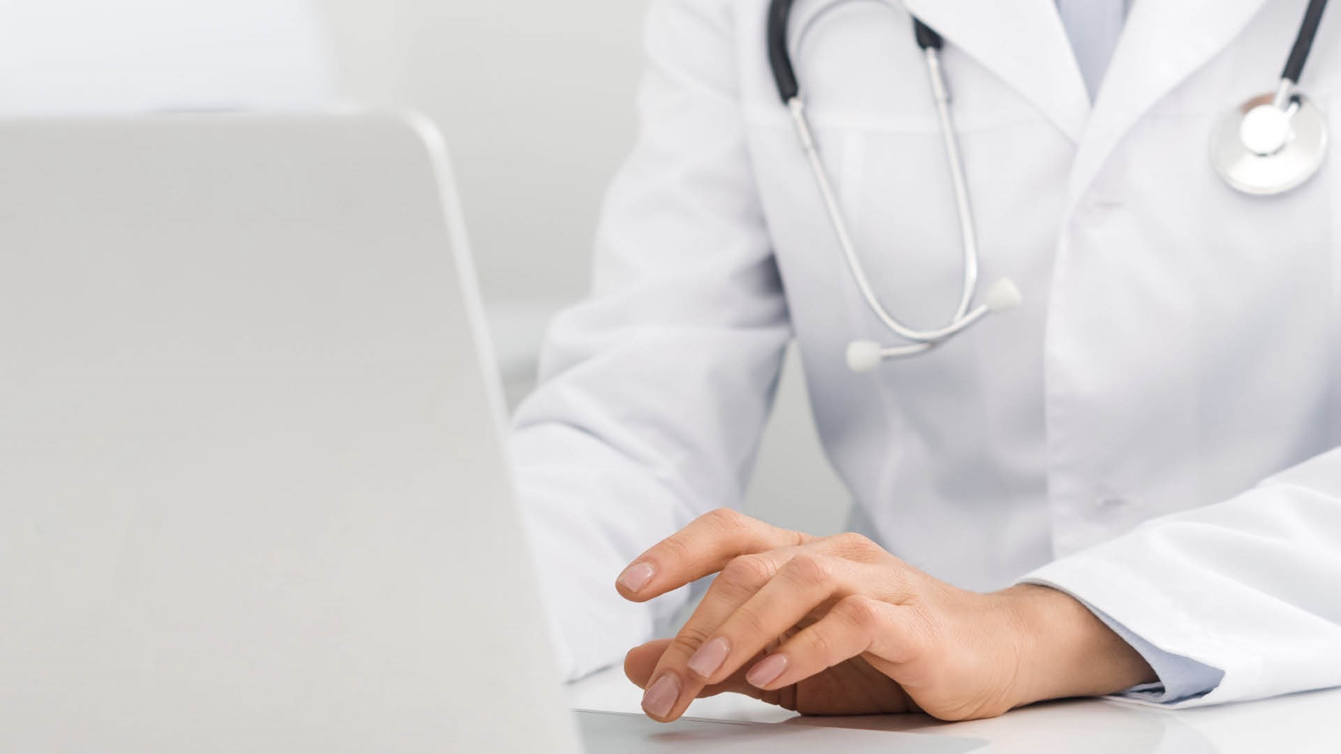 A healthcare professional typing on a laptop, promoting Brainlab Cloud Services